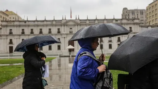 tres personas con paraguas protegiéndose de la lluvia