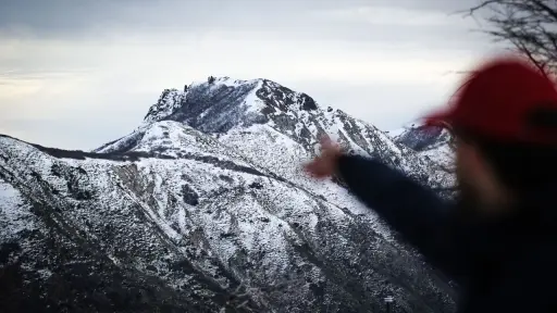 una persona parada frente a una montaña cubierta de nieve