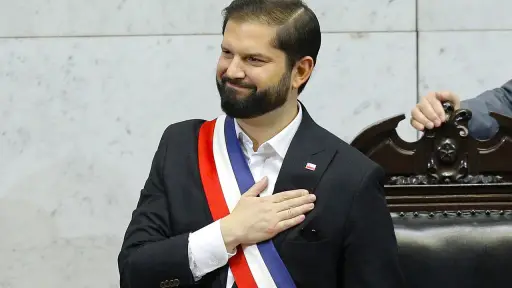 Gabriel Boric de pie junto a un banco