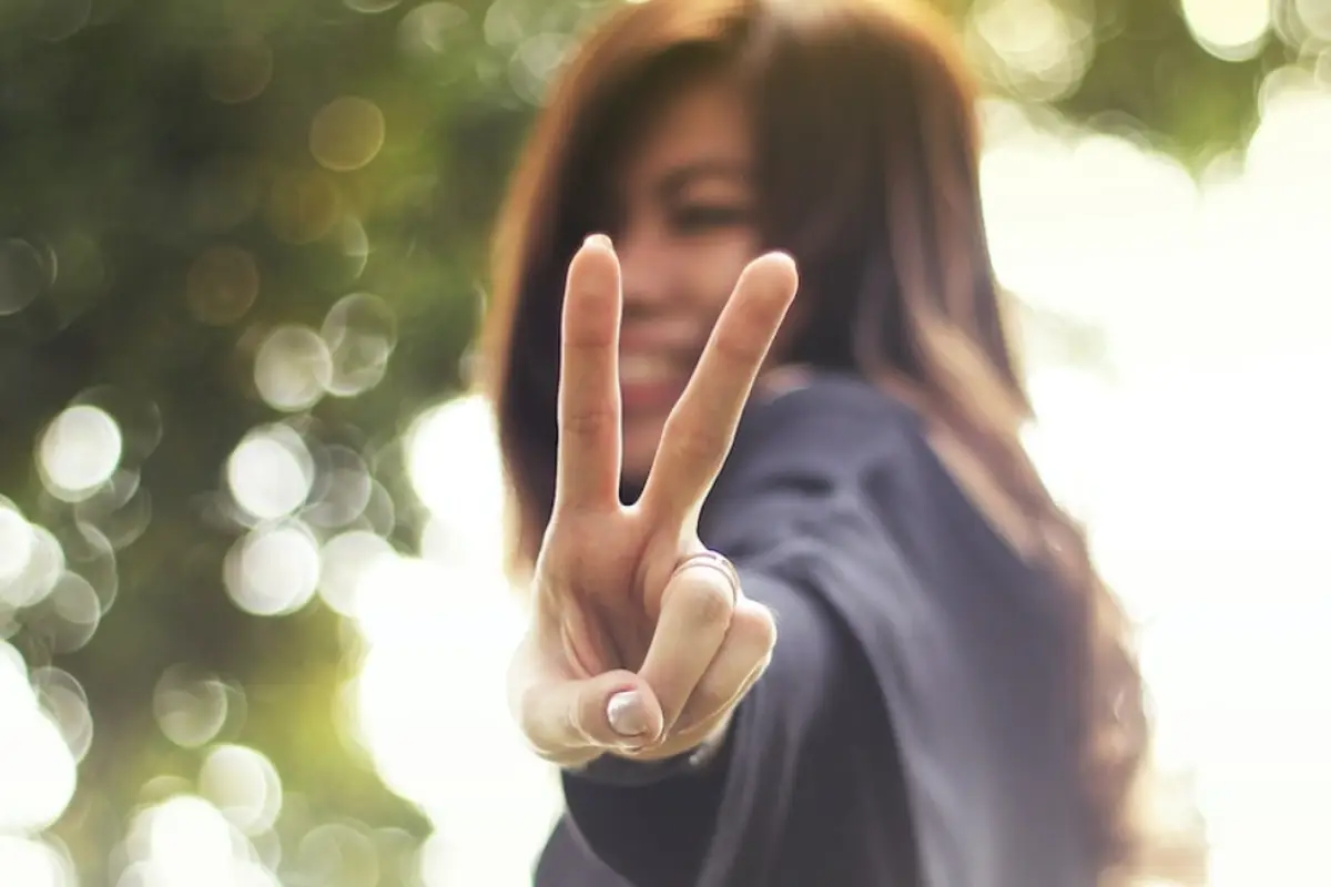 una mujer haciendo el símbolo de la paz con su mano