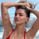 La China Suárez con las manos en la cabeza se sostiene el cabello y posa con bikini rojo en la playa