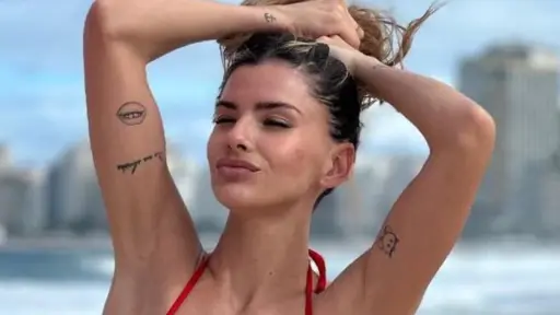 La China Suárez con las manos en la cabeza se sostiene el cabello y posa con bikini rojo en la playa