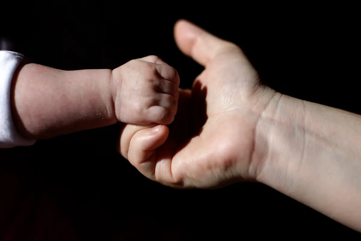 Mano de una lactante junto a la mano de una adulta