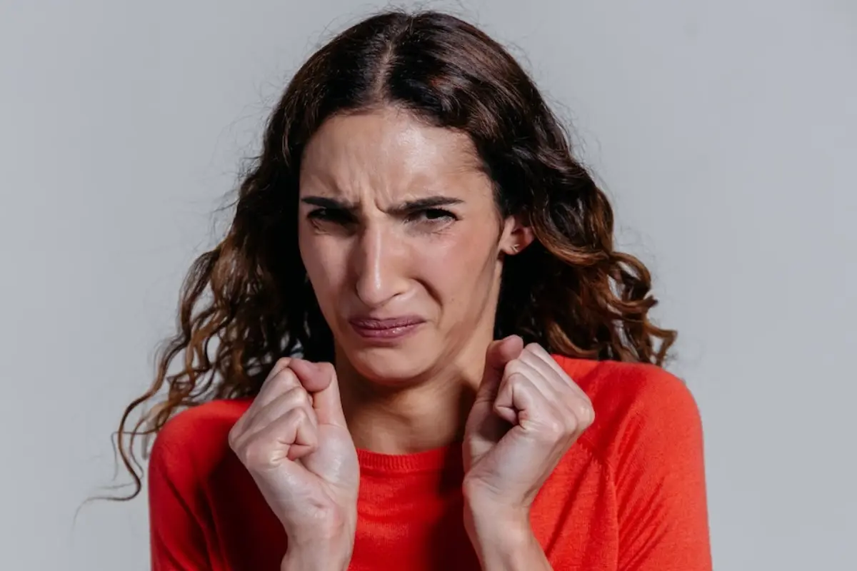una mujer con cara de desagrado aprieta los puños en su pecho