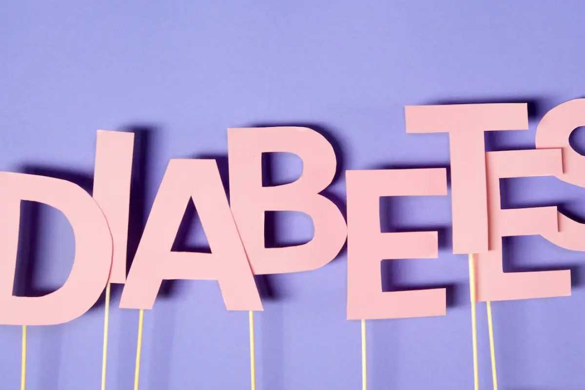 La palabra DIABETES escrita con letras de papel rosa sobre un fondo lila