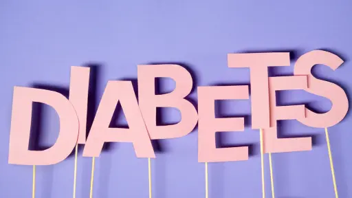 La palabra DIABETES escrita con letras de papel rosa sobre un fondo lila