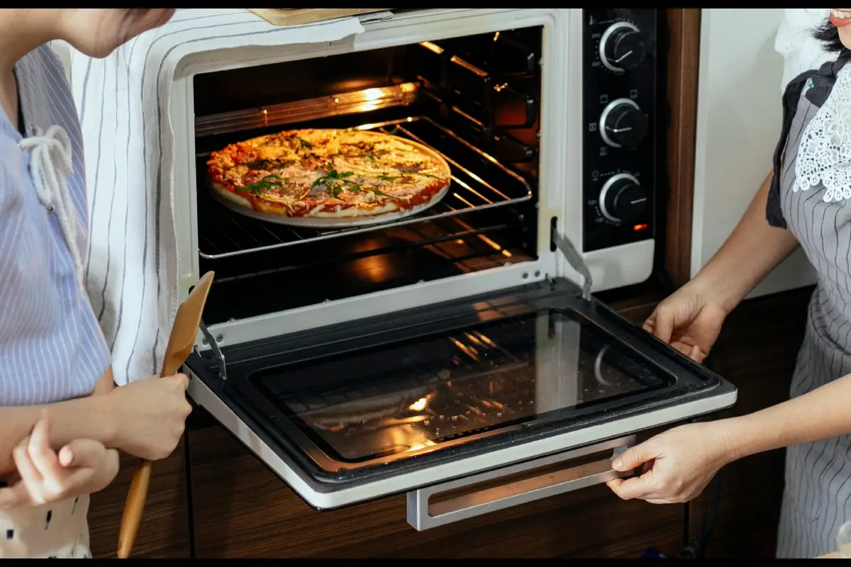 Dos mujeres metiendo una pizza en un horno