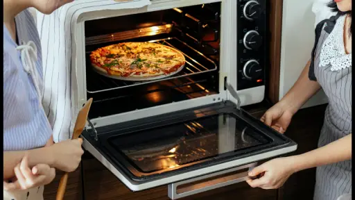 Dos mujeres metiendo una pizza en un horno