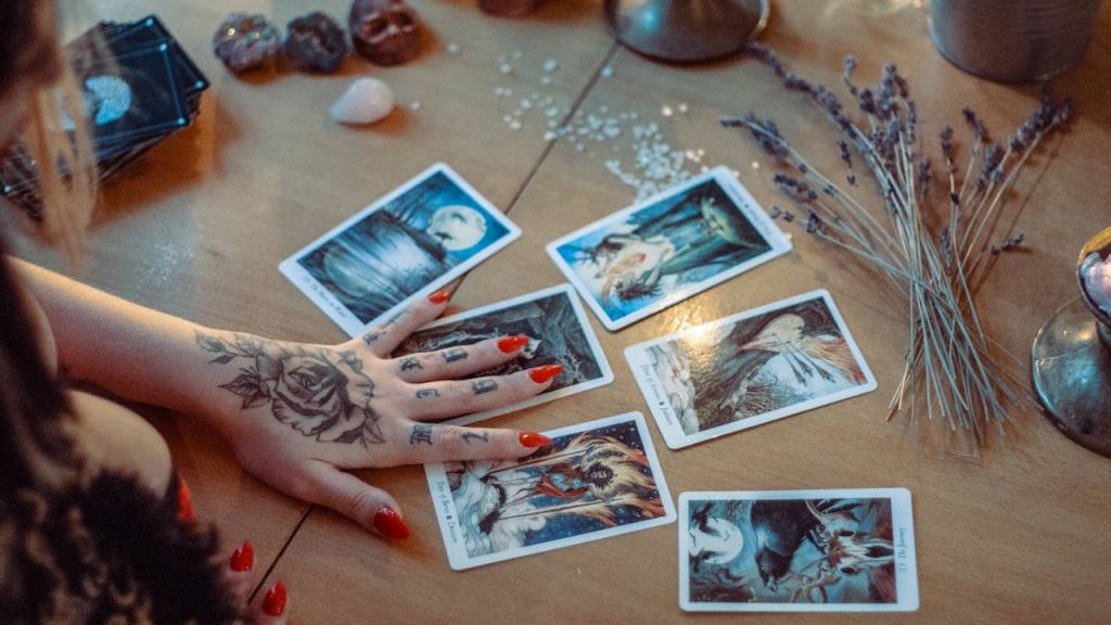 Una mujer que realiza una lectura de tarot en una mesa con varias cartas repartidas / 