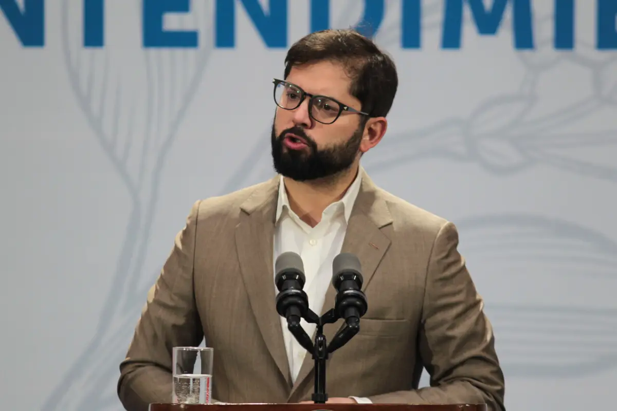 Gabriel Boric con traje beige frente a un micrófono