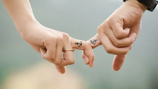 manos enlazadas por los dedos índice con tatuajes de anclas