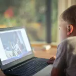 un niño mira una pantalla de computador durante sus vacaciones de invierno
