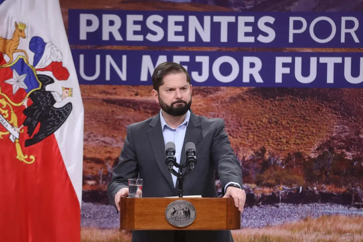 Gabriel Boric con traje tras un micrófono