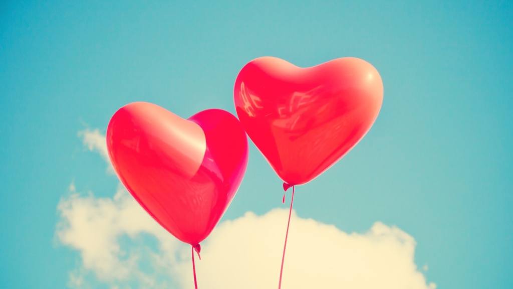 dos globos con forma de corazón representan el amor flotando en el cielo / 