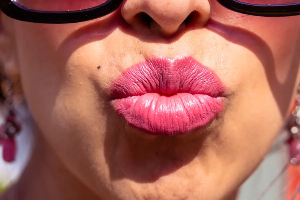 una mujer lanza un beso a la cámara con los labios pintados, besar