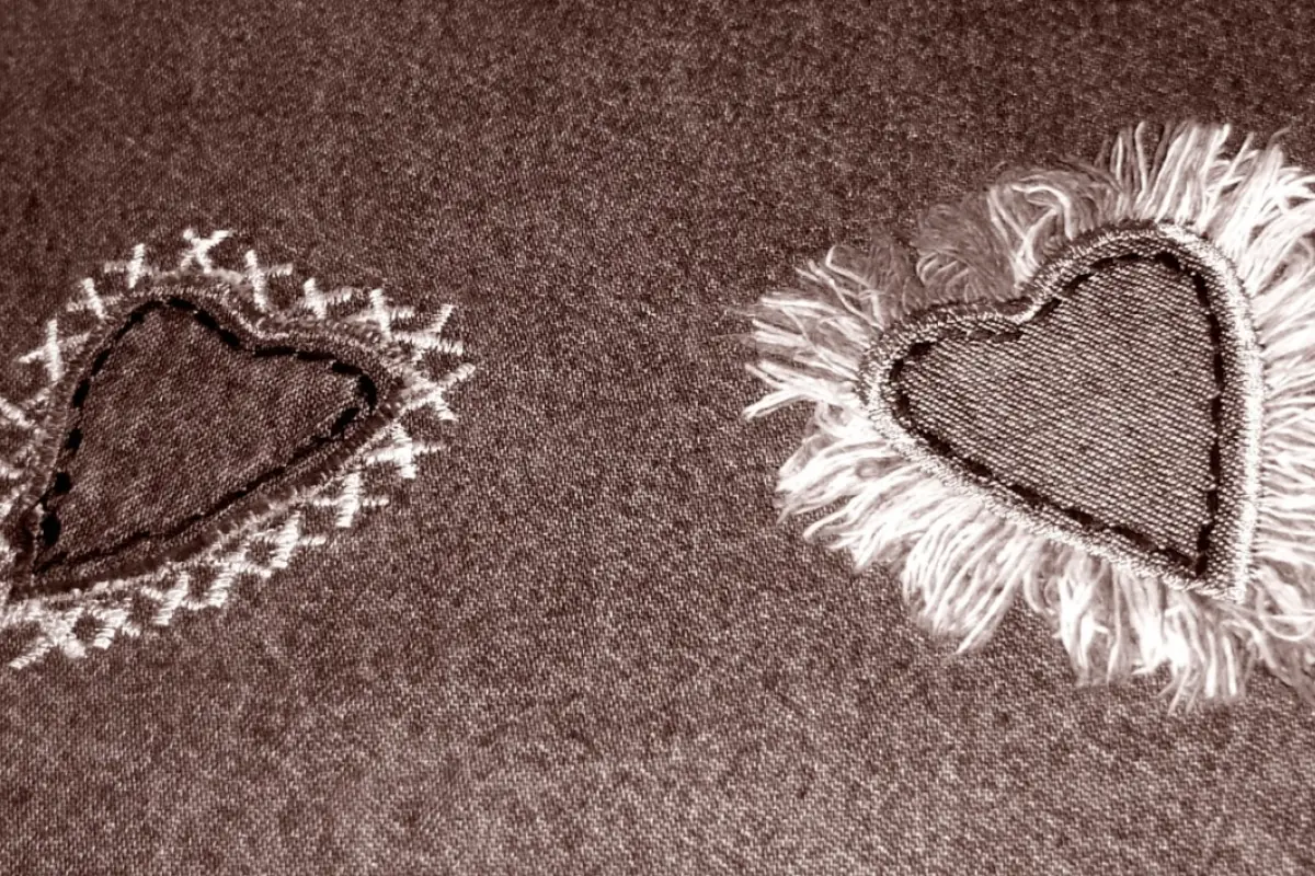 dos corazones bordados sobre una tela gris amor