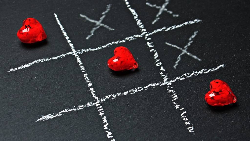 un juego de gato hecho con tiza en el suelo cruzado de tres corazones rojos, amor / 