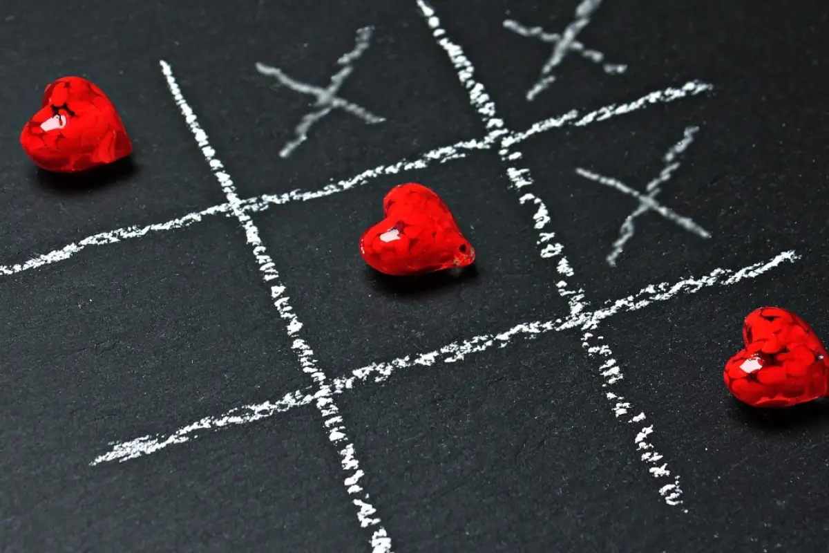 un juego de gato hecho con tiza en el suelo cruzado de tres corazones rojos, amor