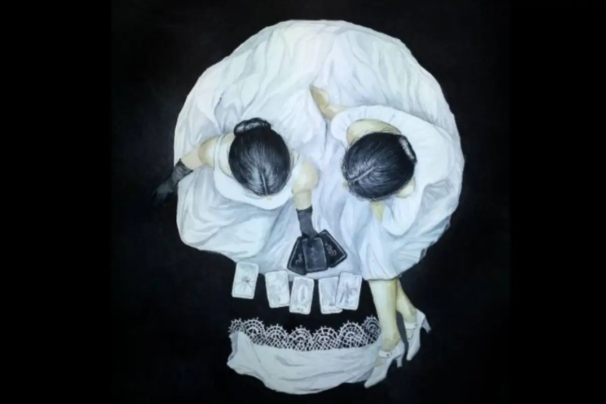 un cráneo formado por dos mujeres sentadas en suelo tomando té y leyendo cartas