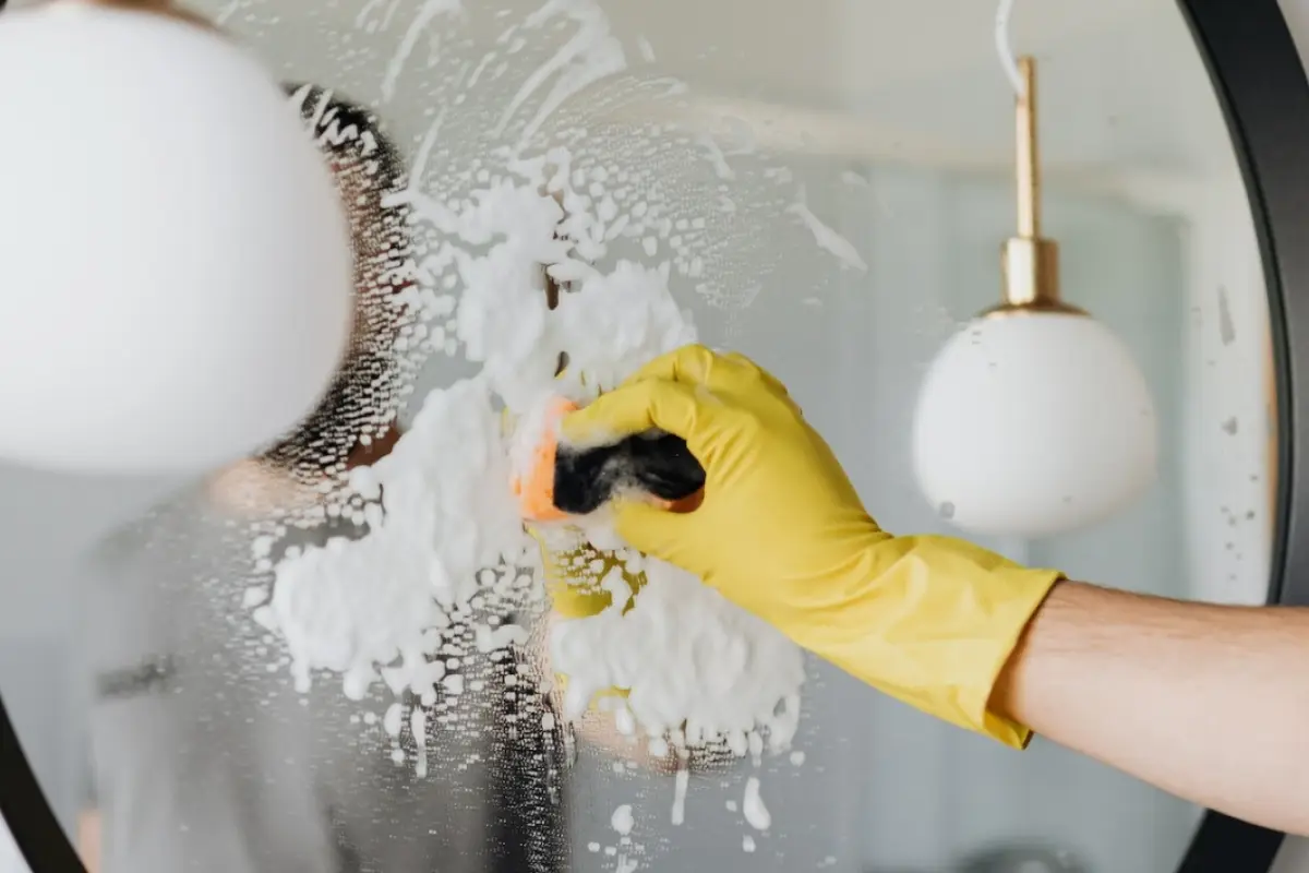 una mano limpiando un espejo para demostrar Truco de limpieza para vidrios impecables