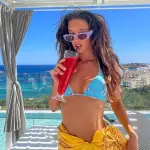 María Pedraza con bikini celeste tomando jugo