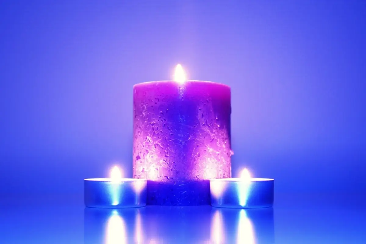 tres velas encendidas en un entorno azulado, para mostrar el hechizo de amor de las velas