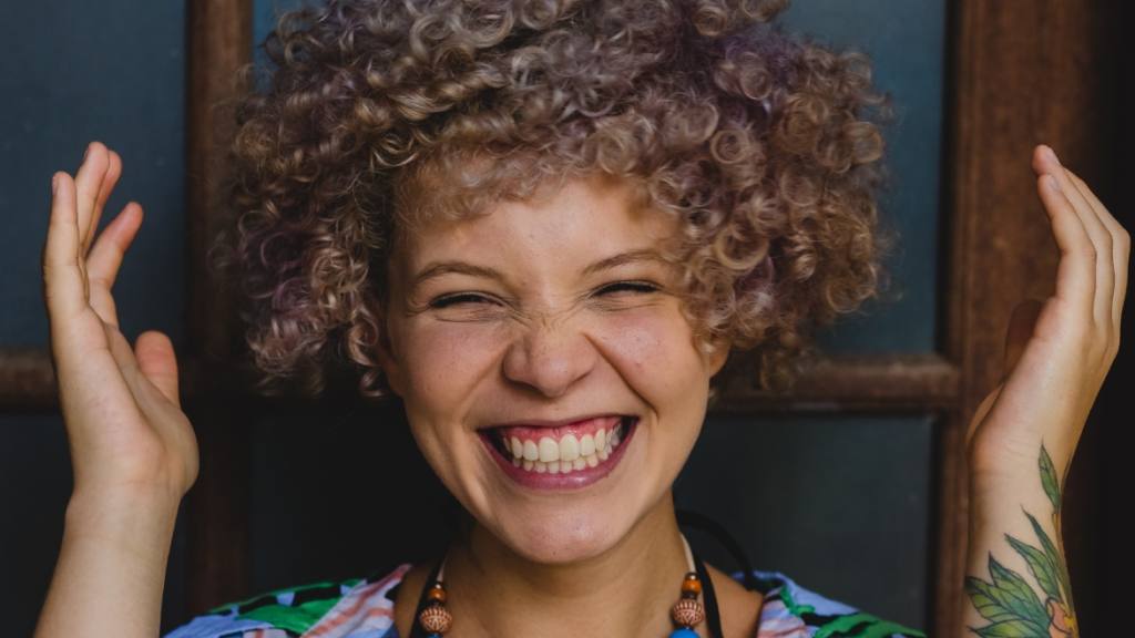 una mujer de cabello rizado sonríe feliz y luce enamorada / 