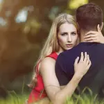 una mujer mira a la cámara por sobre el hombro de su pareja