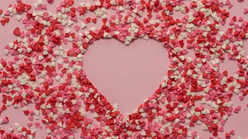 un sinfín de corazones pequeños que forman un corazón más grande sobre un fondo rosado, 