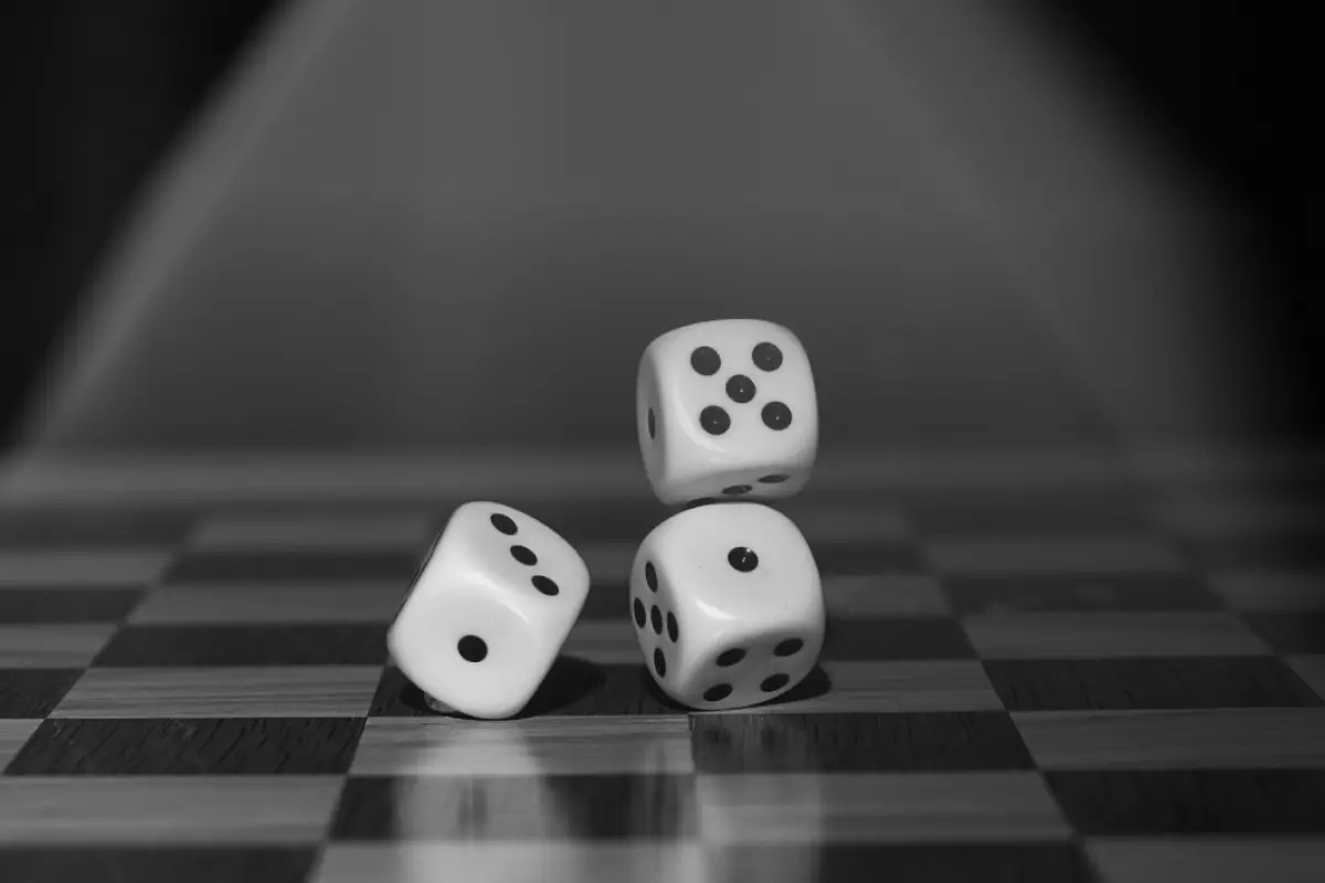 tres dados sobre un tablero de ajedréz que simbolizan la suerte