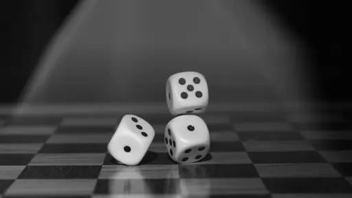 tres dados sobre un tablero de ajedréz que simbolizan la suerte