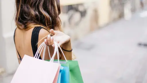 de espaldas, una mujer luego de ir de compras con sus bolsas en la mano