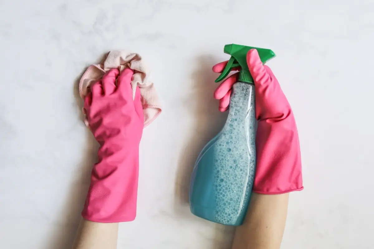 unas manos con guantes de goma que limpian una superficie