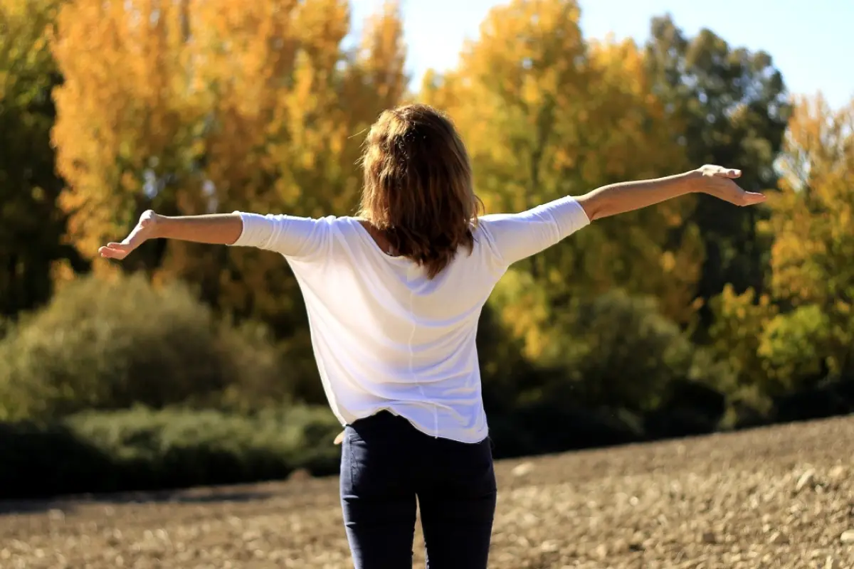 una mujer feliz con los brazos abiertos en medio del bosque disfruta del carpe diem