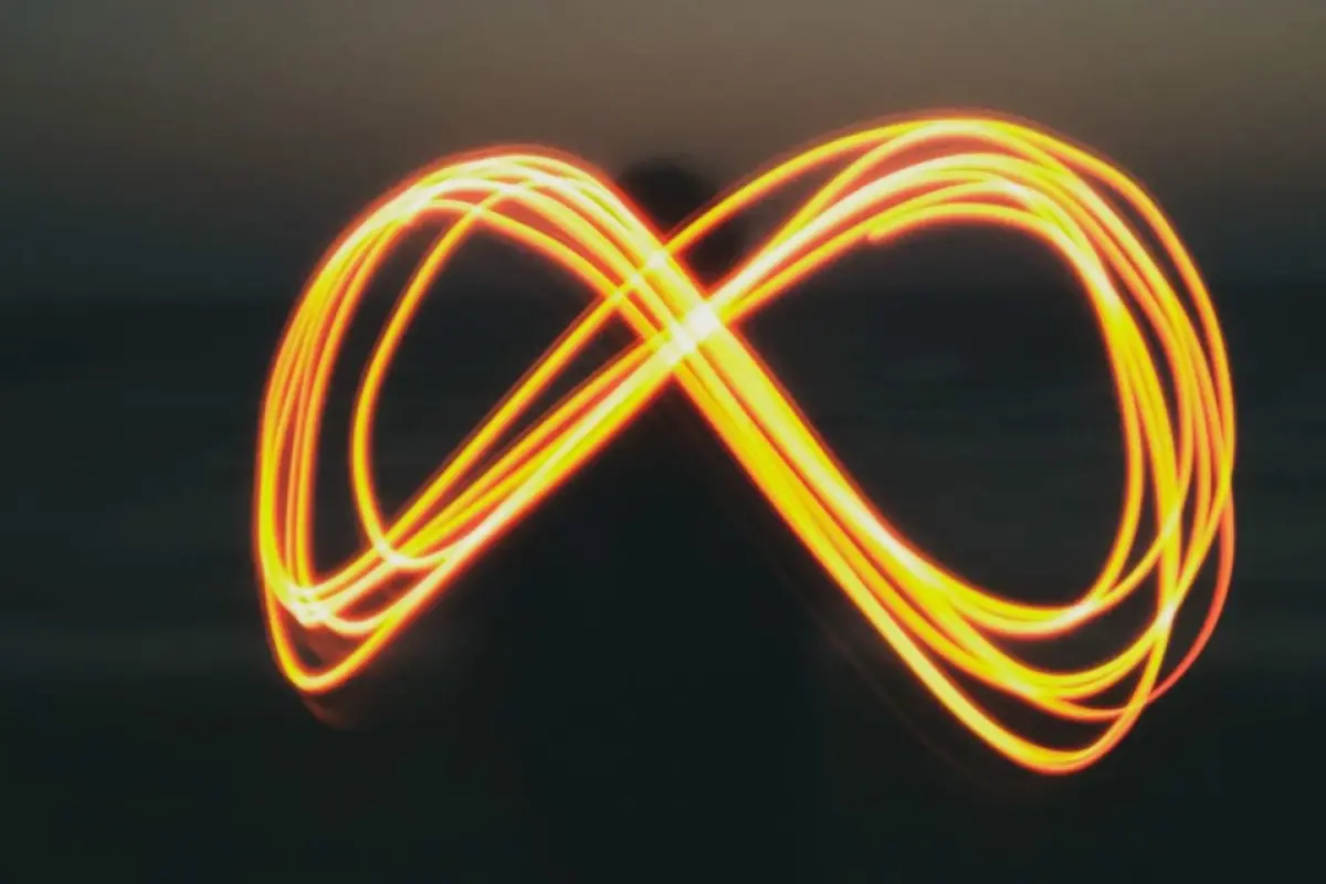 signo del infinito formado por una pesona que dibuja con luz en un atardecer