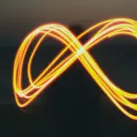 signo del infinito formado por una pesona que dibuja con luz en un atardecer