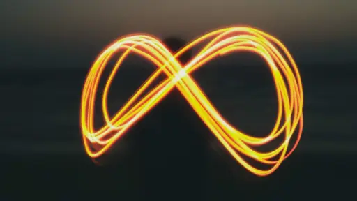 signo del infinito formado por una pesona que dibuja con luz en un atardecer