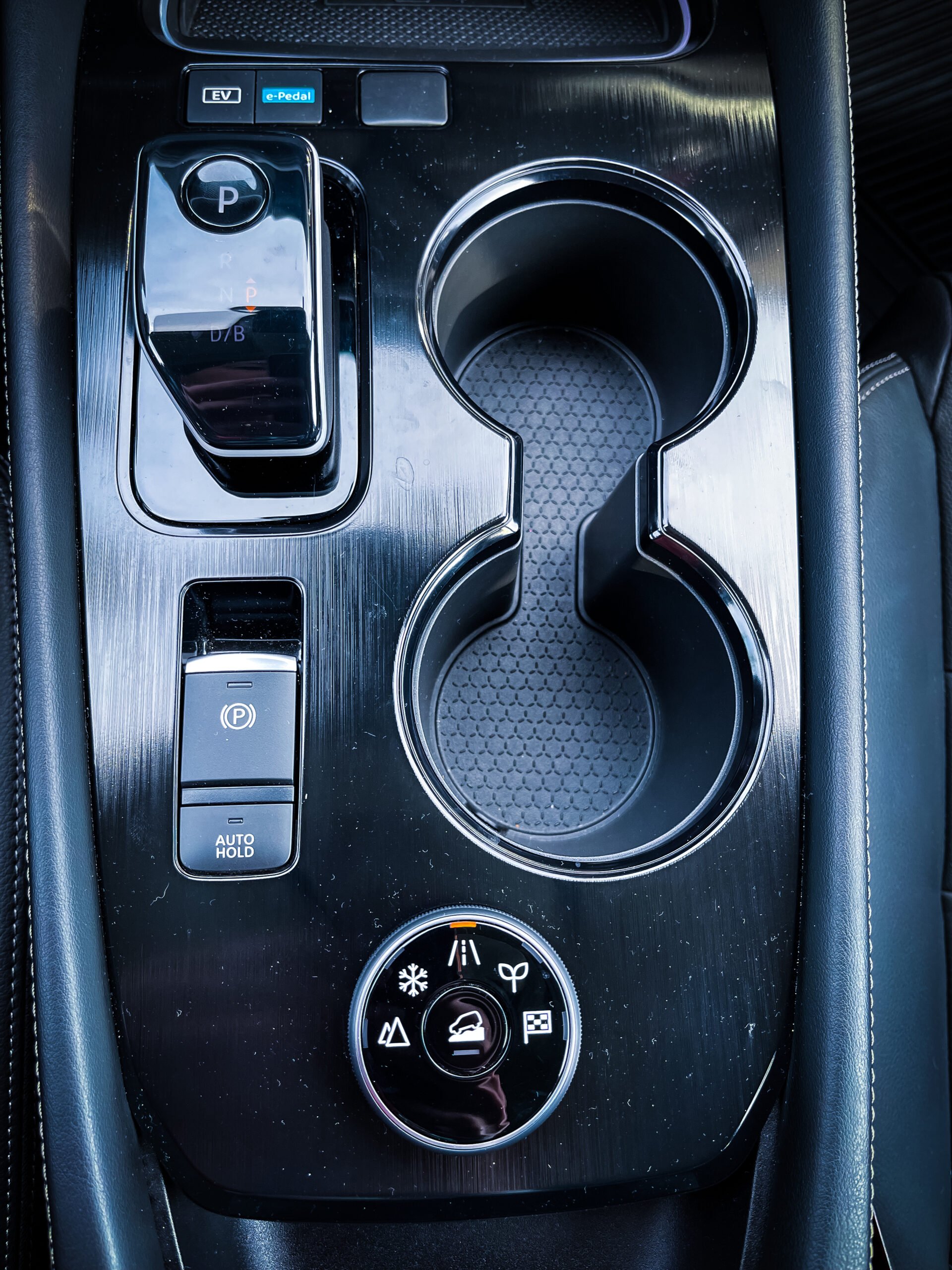 Selector de modos de conducción + palanca de cambios + botón EV + e-Pedal + Freno de mano eléctrico.