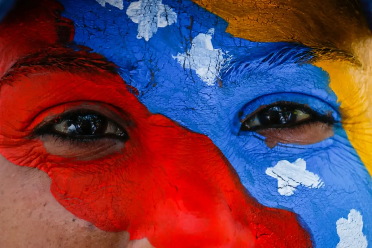 rostro de una mujer con la cara pintada con la bandera de venezuela