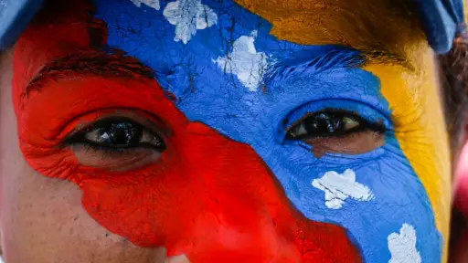 rostro de una mujer con la cara pintada con la bandera de venezuela