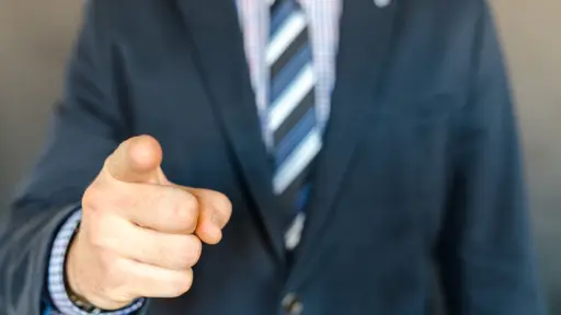un hombre con traje formal apunta a la cámara trabajo, 