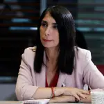 Karla Rubilar con un blazer rosado frente a un micrófono