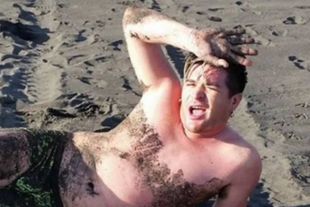 Junior Playboy recostado en la arena de una playa