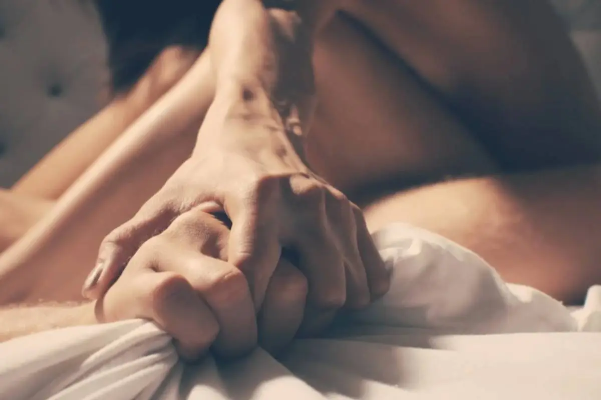 primer plano de pareja tomada de la mano en medio de una relación sexual