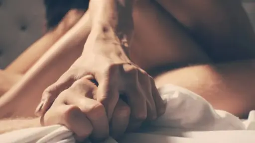 primer plano de pareja tomada de la mano en medio de una relación sexual
