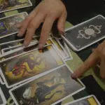 manos de una persona leyendo las cartas del tarot sobre la mesa