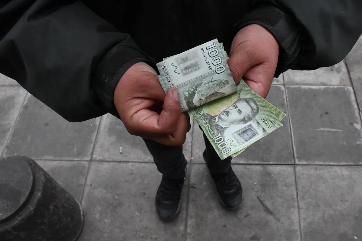 persona contando billetes de mil pesos