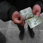 persona contando billetes de mil pesos