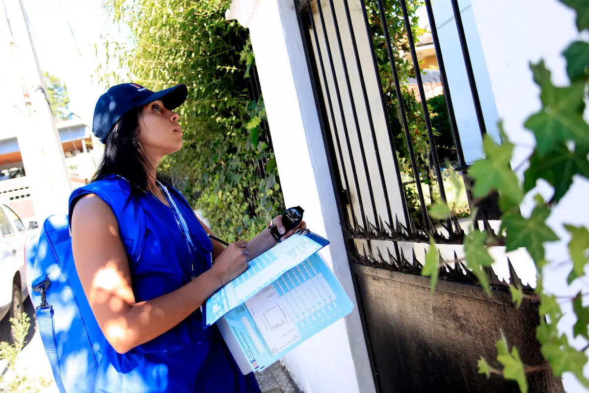 mujer trabajando como encuestadora del censo nacional afuera de una casa
