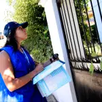 mujer trabajando como encuestadora del censo nacional afuera de una casa